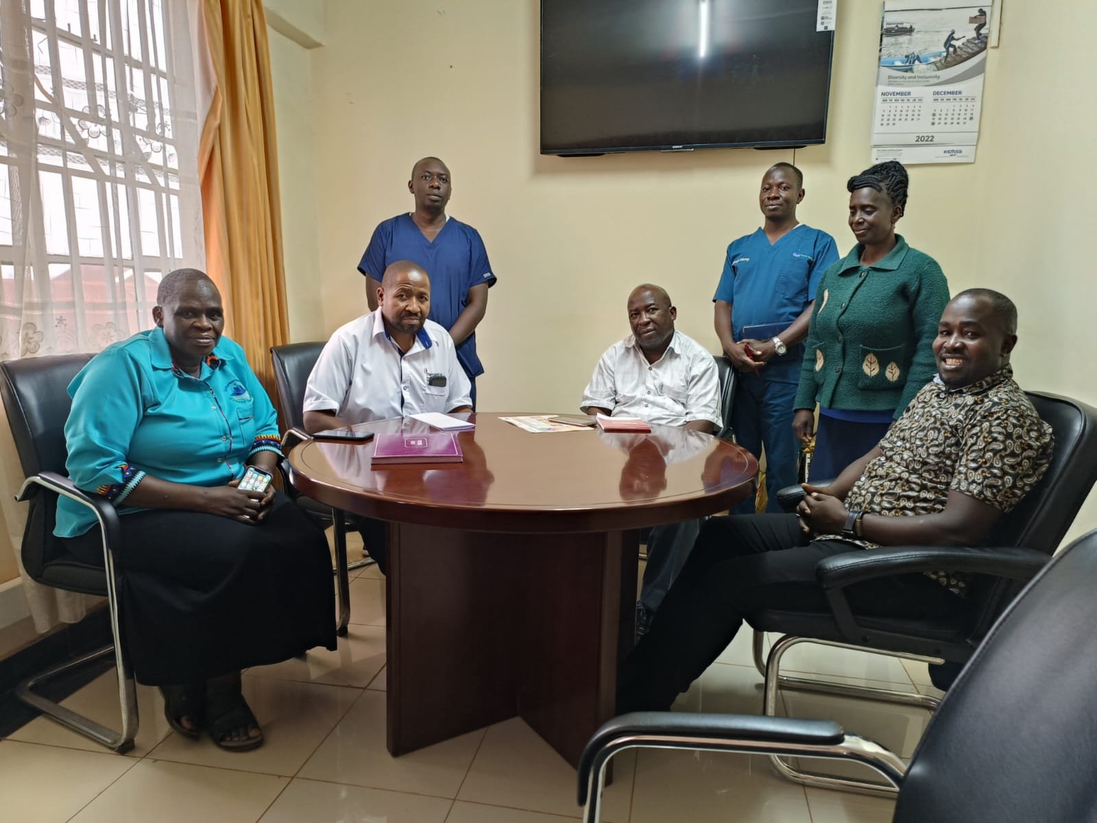 Nyamira County Health Executive Dr.Timothy Ombati Mokua (R) poses in a photo with partners from the International Cancer Institute in his office.